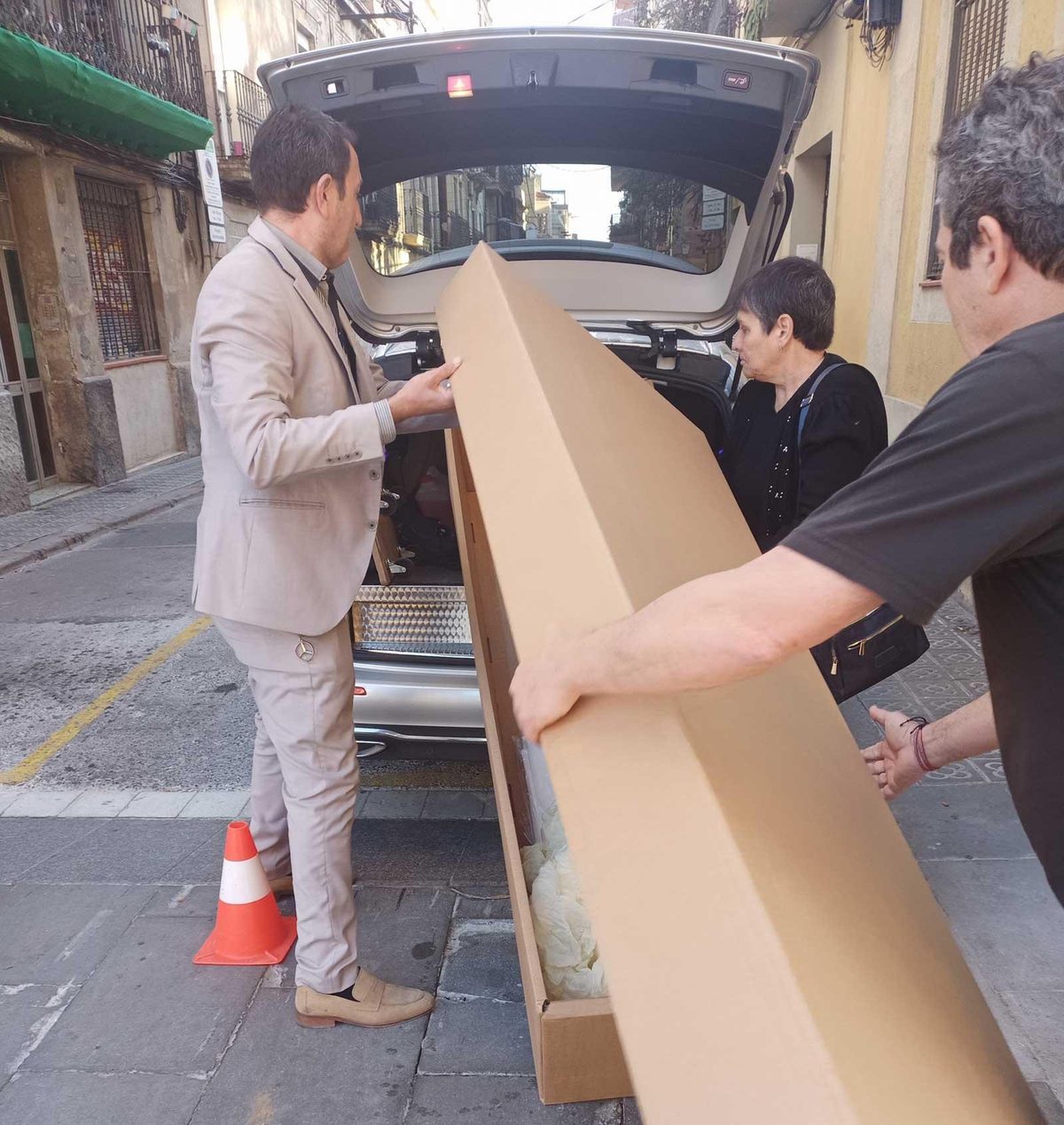 Personal de Funeraria Millenium descargando un ataúd de cartón de un coche fúnebre para una cremación directa